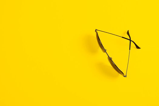 Sunglasses on yellow background. Minimalistic summer banner with copy space.