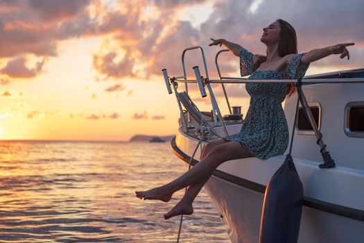 Young attractive woman sitting on the deck of the yacht and enjoying sunset