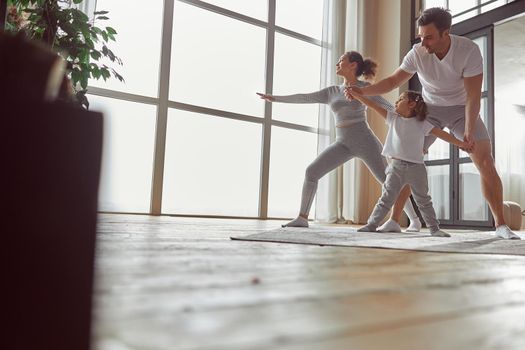 Low angle of calm woman in asana while man is showing little girl how to exercise