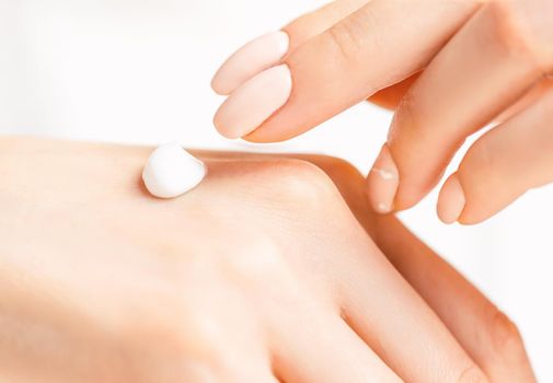 Close-up of female hands applying moisturizing cream, concept of skincare and beauty.