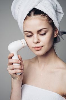 woman with towel on head facial massager skin care hygiene. High quality photo