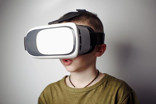Boy playing mobile game app on device virtual reality glasses on white background. Boy action and using in virtual headset, VR box for use with smart phone. Contemporary technology concept, close up