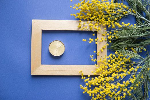 Spring concert. Mimosa and gold frame on blue background. Mimosa close-up. Happy spring. Space for text.