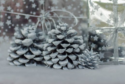 Cones in the snow and presents in silver packing for Christmas