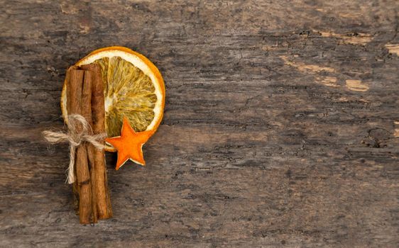 A pile of cinnamon sticks, dried orange and tangerine stars on old wooden table with copy space. Christmas decoration. Christmas card.