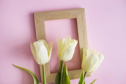 Yellow Tulip flowers are arranged on a pink background. The view from the top, flat lay. Empty space for the text. Spring concept. Women's day. Mother's day.