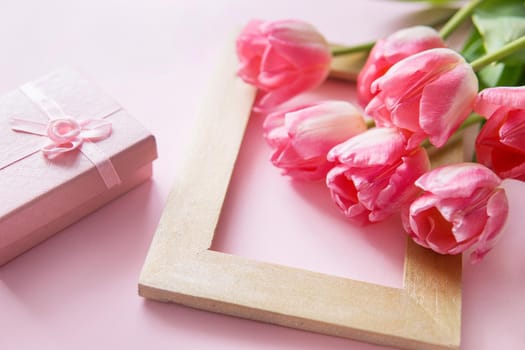 Pink and yellow Tulip flowers, gift boxes are arranged on a pink background. The view from the top. Сoncept of spring. Women's day. Mother's day.