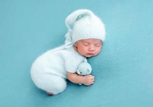 Cute sleeping newborn in knitted blue suit