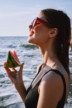 woman in black swimsuit with watermelon by the ocean. High quality photo