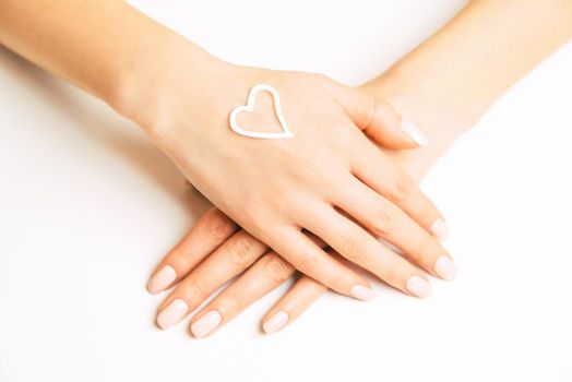Skincare moisturizing cream in shape of heart on a female young hand, concept of beauty.