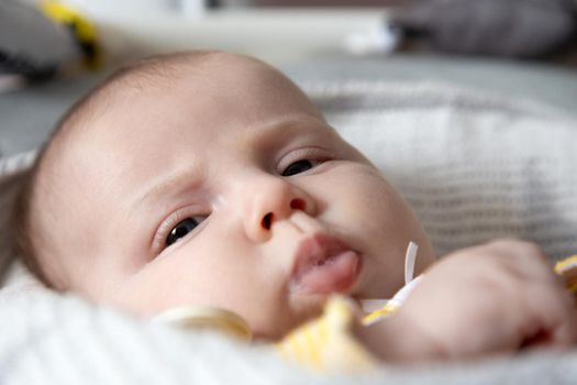 A close-up portrait of a newborn baby girl who drooling. three-month-old baby lies in a cradle and reskeries milk. High quality photo