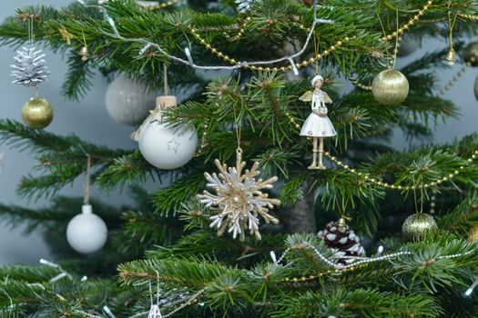 Gold white and argent toys hanging on a Christmas tree