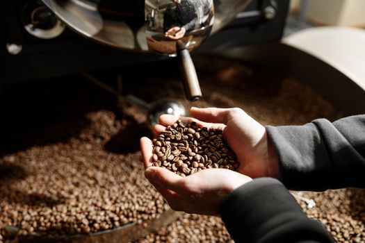 Young specialist worker is roasting coffee in hangar