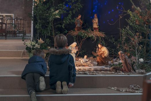 Children look at christmas creche with Joseph Mary and small Jesus