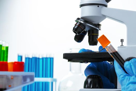 Scientist's hands doing chemical research with the help of microscope, close up