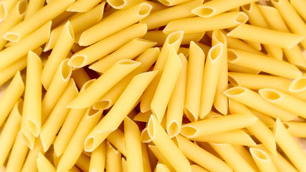 Penne Rigate Raw Pasta is a short pasta with oblique cuts and a ribbed surface. Traditional Italian pasta. Pasta background. Italian food ingredient top view
