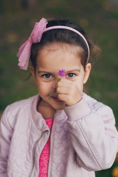 Young girl in a pink jacket and pink leggings in the park.