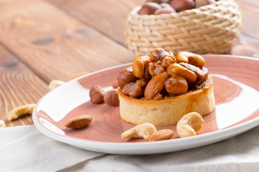 Tart with nuts on pink plate close up. Pastry