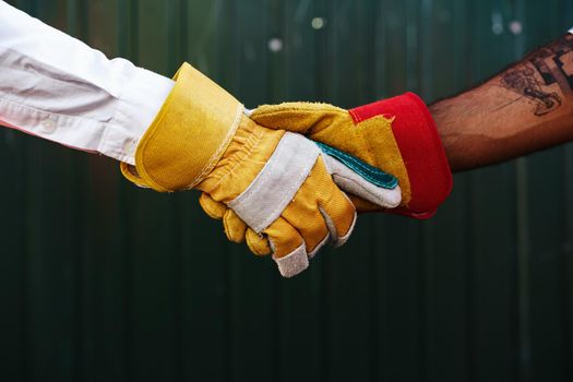 Close up photo photo of two men builders in workwear shaking hands