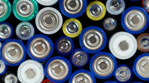Lots of used household alkaline batteries type AA, AAA, collected for recycling. Recycling and ecology problems. Top view of a background of used batteries of different types and sizes