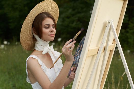 Woman in white dress outdoors artist drawing easel. High quality photo