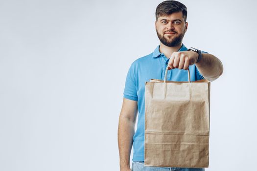 Delivery man with bag order from groceries on light grey background