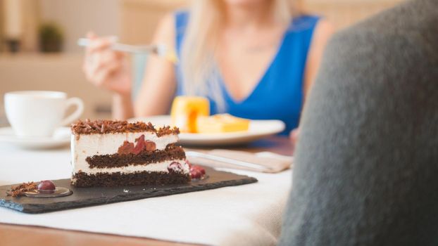 Two caucasian people in the cafe enjoying the desserts and talking, close up