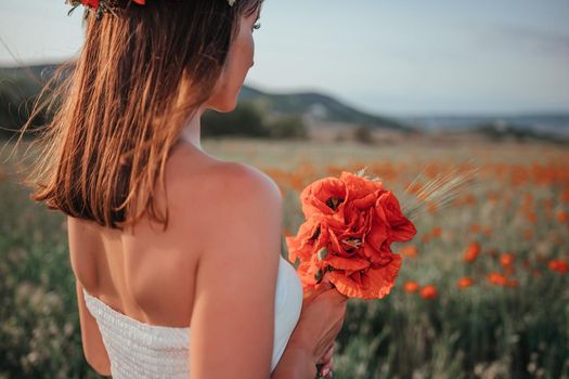 Bride in a white dress holding a bouquet of poppy flowers, warm sunset time on the background of the lavender field. Copy space. The concept of calmness, silence and unity with nature.