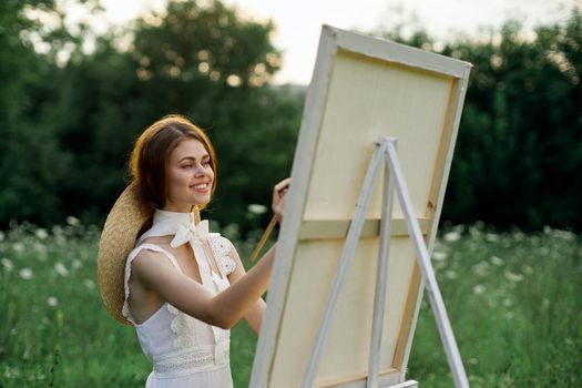 Woman in white dress paints a picture outdoors hobby creative. High quality photo