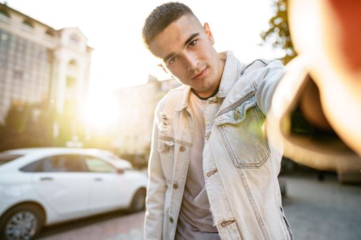 Portrait of young man taking a selfie while out on the city street, close up selfie