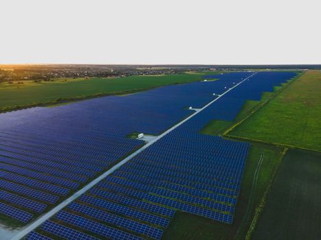 Aerial drone view of large solar panels at a solar farm at bright summer sunset. Solar cell power plants, colorful photo