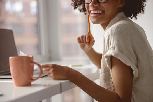 Cropped photo of happy female worker enjoying her job in office while holding documents