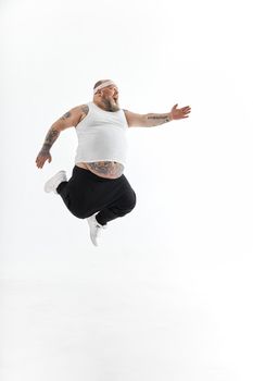 Happy fat man with big belly and tattoes in sports wear posing on white background