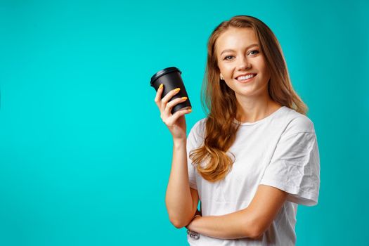 Young attractive woman holding a cup of hot drink against blue background