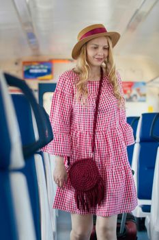 Young caucasian woman in hat with wavy hair smiling in speed train, close up