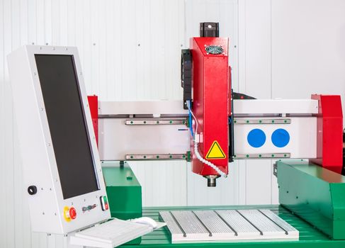 Automated CNC equipment for working with metal at factory near the wall. The programmed robot head. Telephoto shot