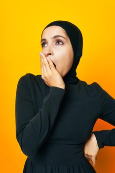 pretty woman in black hijab posing fashion hand gesture yellow background. High quality photo