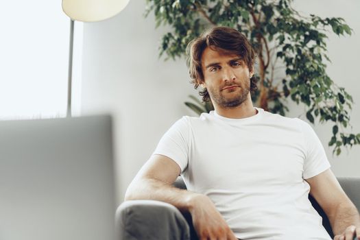 Relaxed casual man sitting on the sofa and looking at camera, man portrait