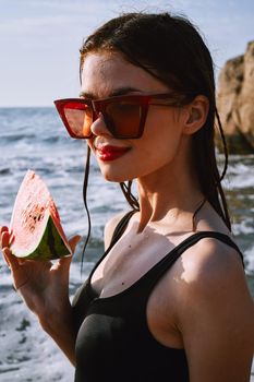 woman in black swimsuit with watermelon by the ocean. High quality photo