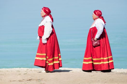 20 August 2018, Krasnovidovo, Russia - mature women in russian folk costume walking on a background of water