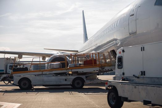 Baggage on conveyor belt unloaded from an airplane outdoors on a daytime. Plane, shipping, transportation concept