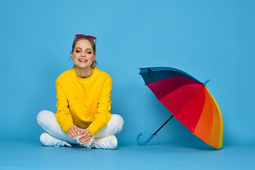 woman with multicolored umbrella in yellow sweater posing rainbow colors. High quality photo