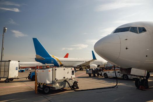 View of white airplane during refueling at airport outdoors on a daytime. Aircraft details. Plane, shipping, transportation concept