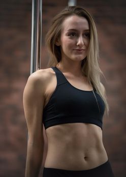 Young pretty woman in sport bra staying next by the pole. Portrait