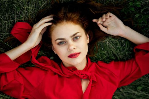 woman in red dress lies on the grass address fashion summer. High quality photo