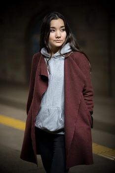 Photo of young woman in night subway. Full body. Looking to the side