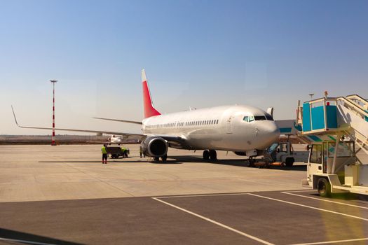 Airplane is parked near gate of airport terminal on sunny day