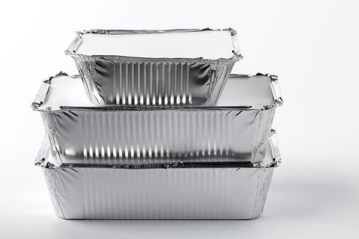 Takeaway meal in foil food box on white background close up