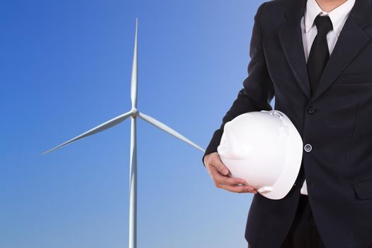engineer holding white helmet with wind turbine background