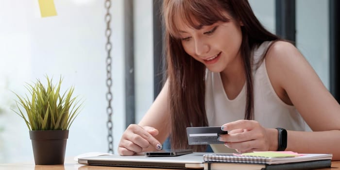 Smiling woman use mobile phone for shopping online with credit card.